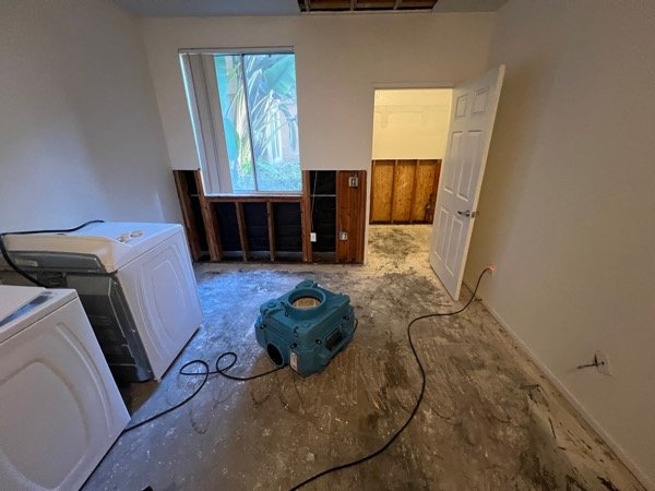 Laundry room with flood-cut drywall exposing wall studs and insulation