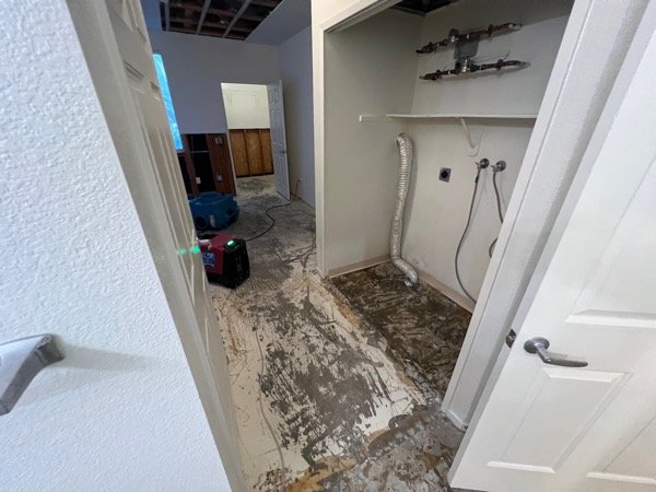 Utility closet with exposed shutoff valves and water-damaged flooring