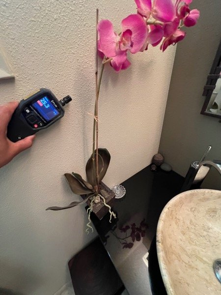 Thermal moisture meter placed on tile floor near a baseboard