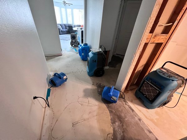 Air movers and dehumidifiers positioned in a living room for structural drying