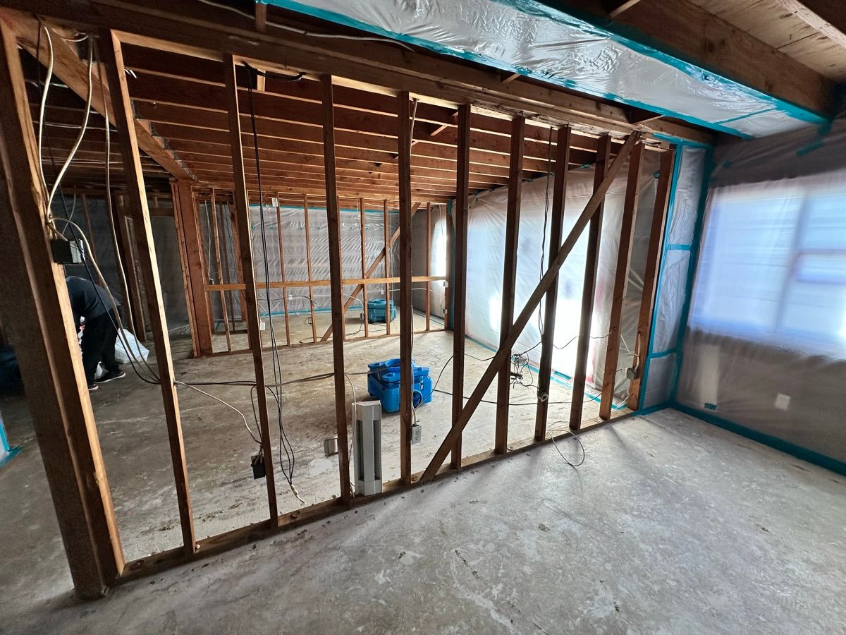 Wall framing exposed with dehumidification equipment running during a San Diego water damage restoration project